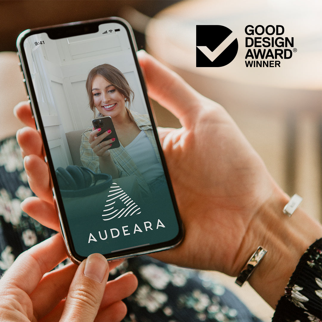 Photo of a hand holding a phone with the Audeara Mobile app open with Good Design Award logo in the top right corner