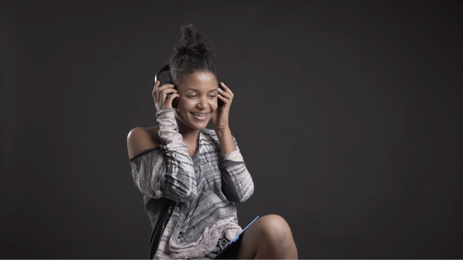 A woman wearing Audeara headphones smiling and grooving to music