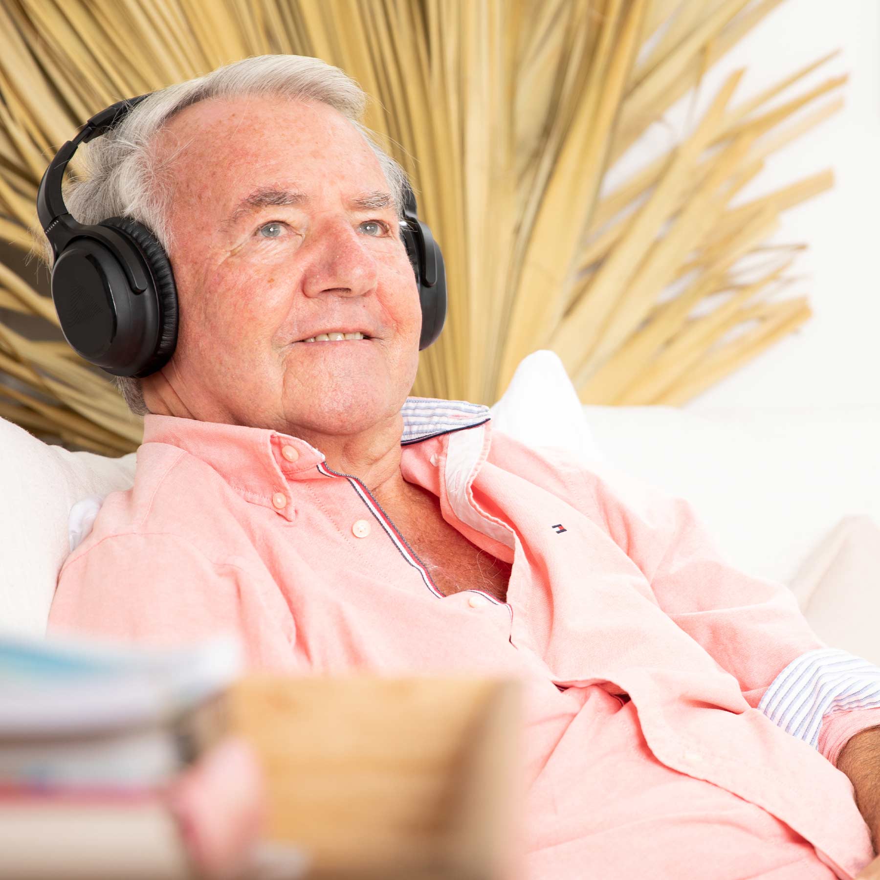 A man smiling contently sitting on the couch while listening to music on his Audeara headphones
