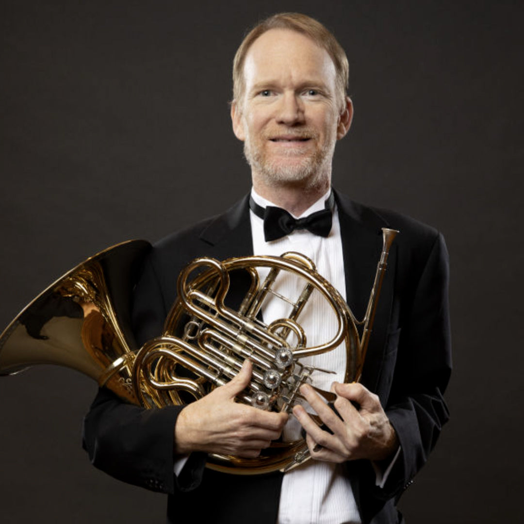 Ian O'Brien in a tuxedo holding a French horn